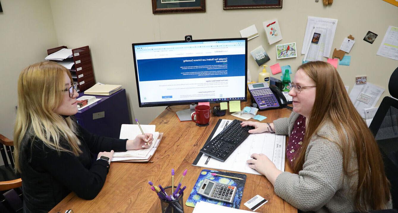 A financial aid worker meets with a student in her office