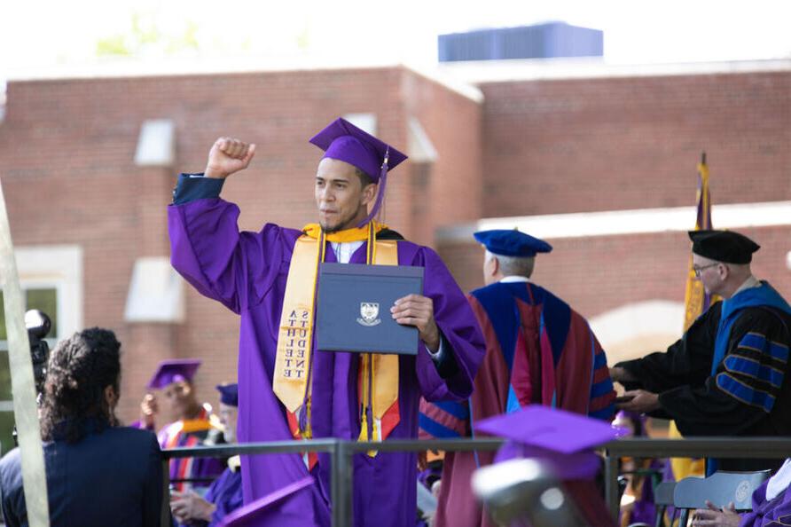 A graduate pumps his fist after receiving his college degree