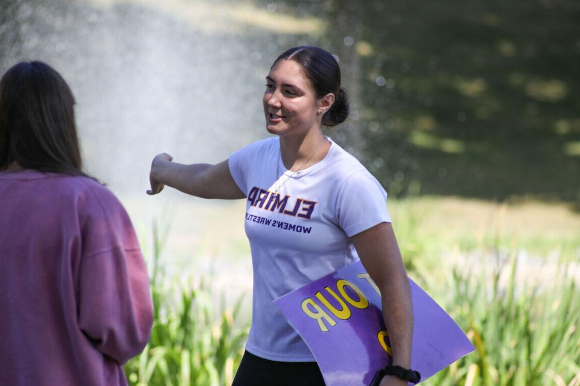 A female student leads a campus tour by the Puddle